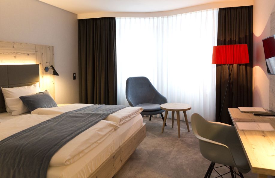 Zimmer Nordic Ausstattung mit Sessel, Bett und roter Lampe
