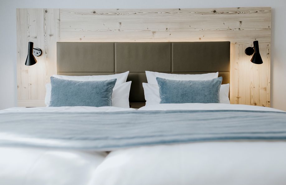 Gemütliches Doppelbett im Zimmer Nordic mit blauen Kissen und blauer Decke