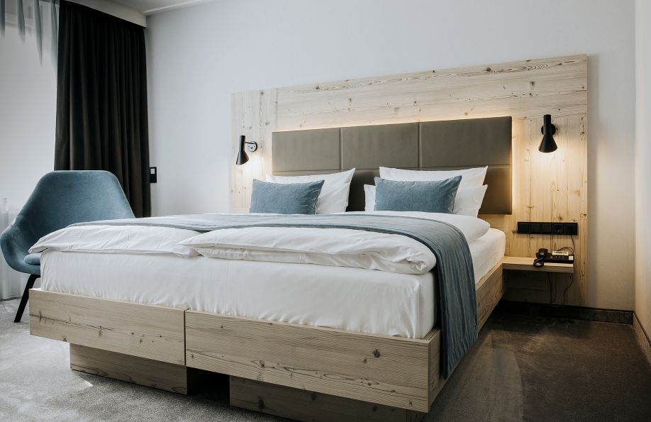 Gemütliches Doppelbett im Zimmer Nordic mit gemütlichem Sessel daneben