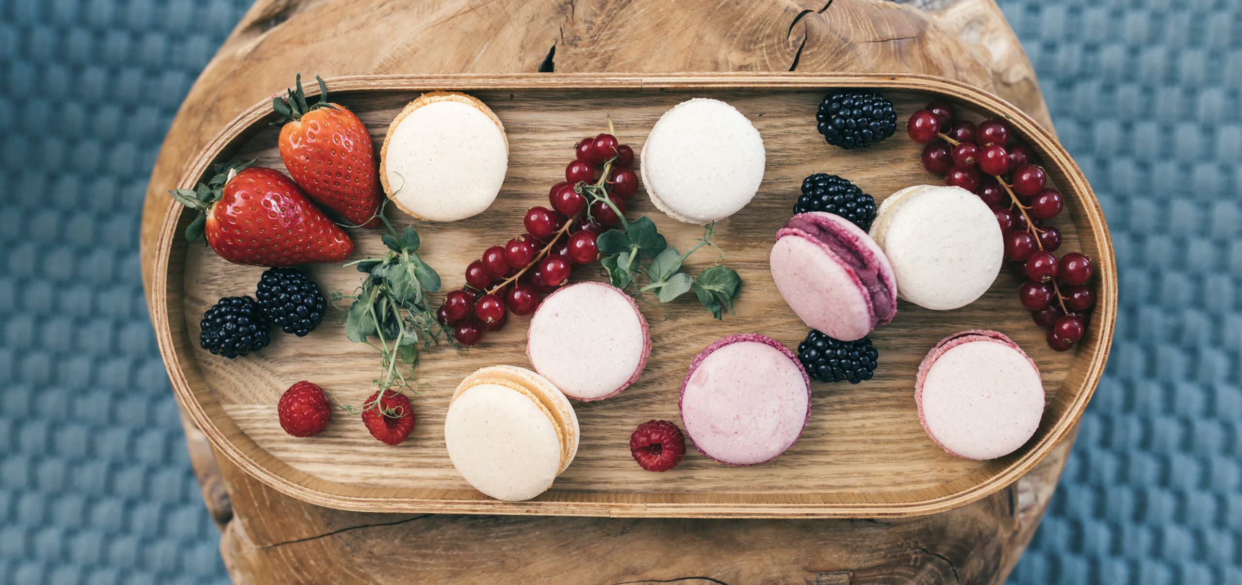 Macarons angerichtet auf einem Holztablett mit diversen Früchten